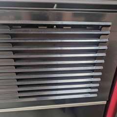 Grille de soufflage en acier noir sur la façade supérieure du poêle à pellets.