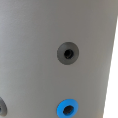 Détail d'un orifice de raccordement de l'eau froide avec insert de couleur bleue.