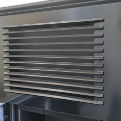 Grille de soufflage d'air chaud en acier noir sur la façade supérieure du poêle.